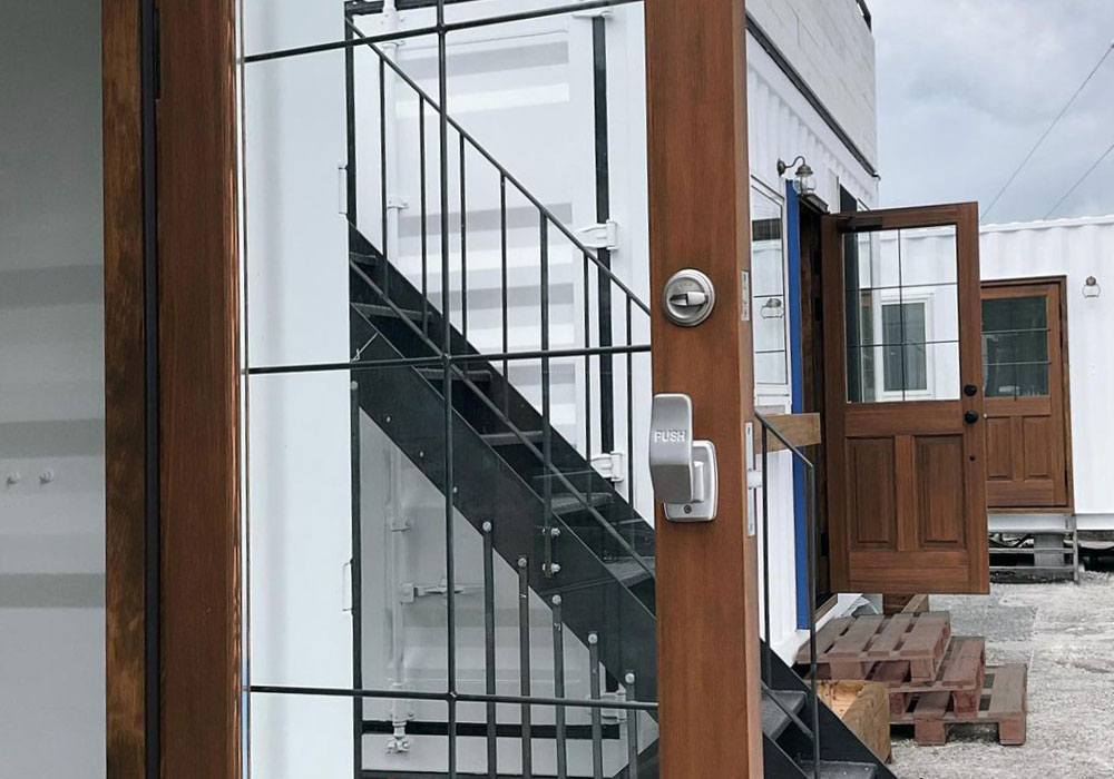 黒いコンテナに映える重厚な木製ドアの外観