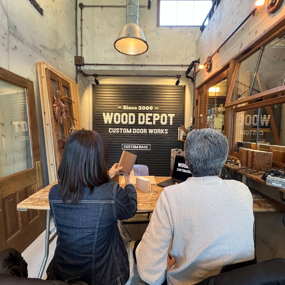 ショールームで木製ドアの質感を確認するお客様