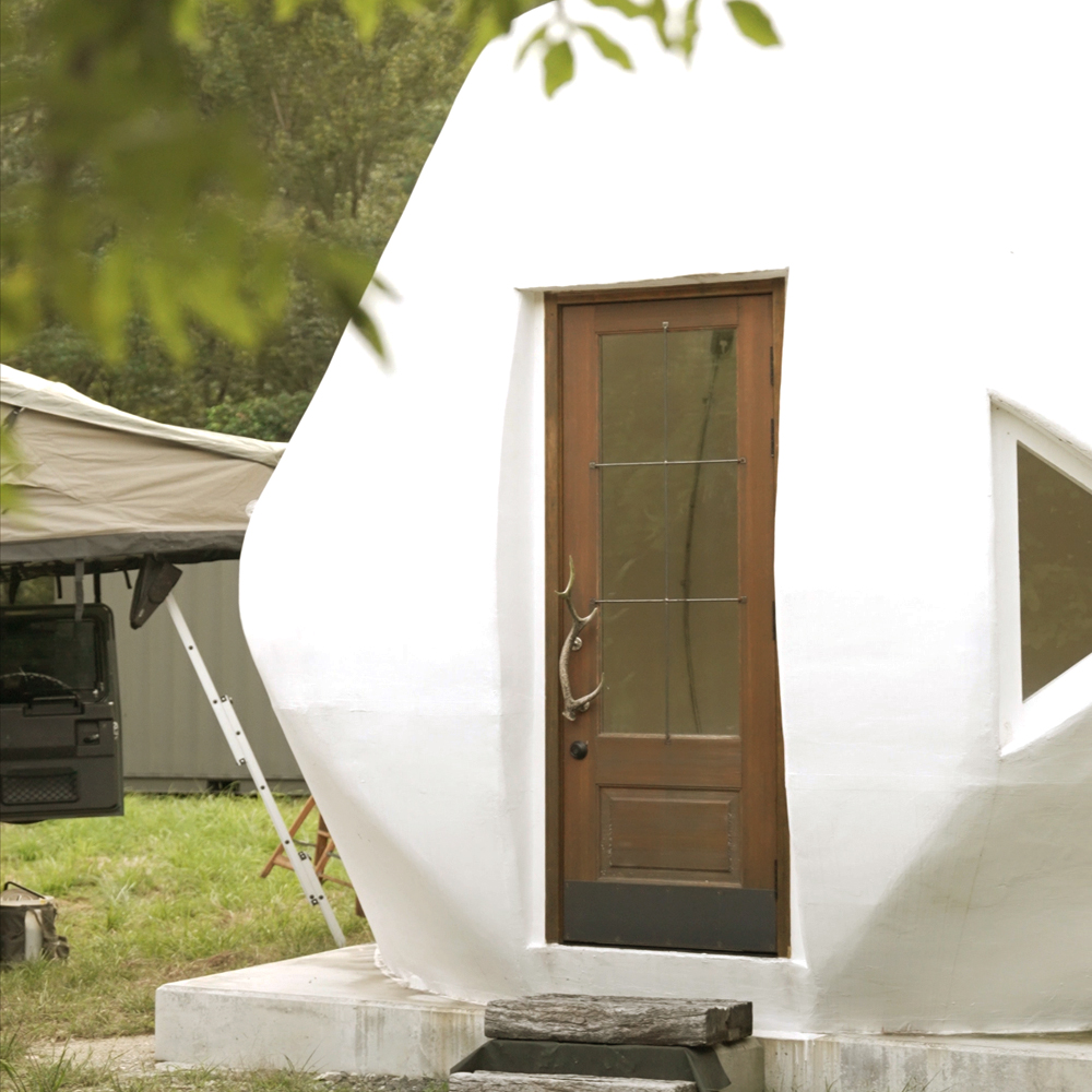 白い滑らかな壁に嵌め込まれたヴィンテージ仕上げの木製玄関ドア