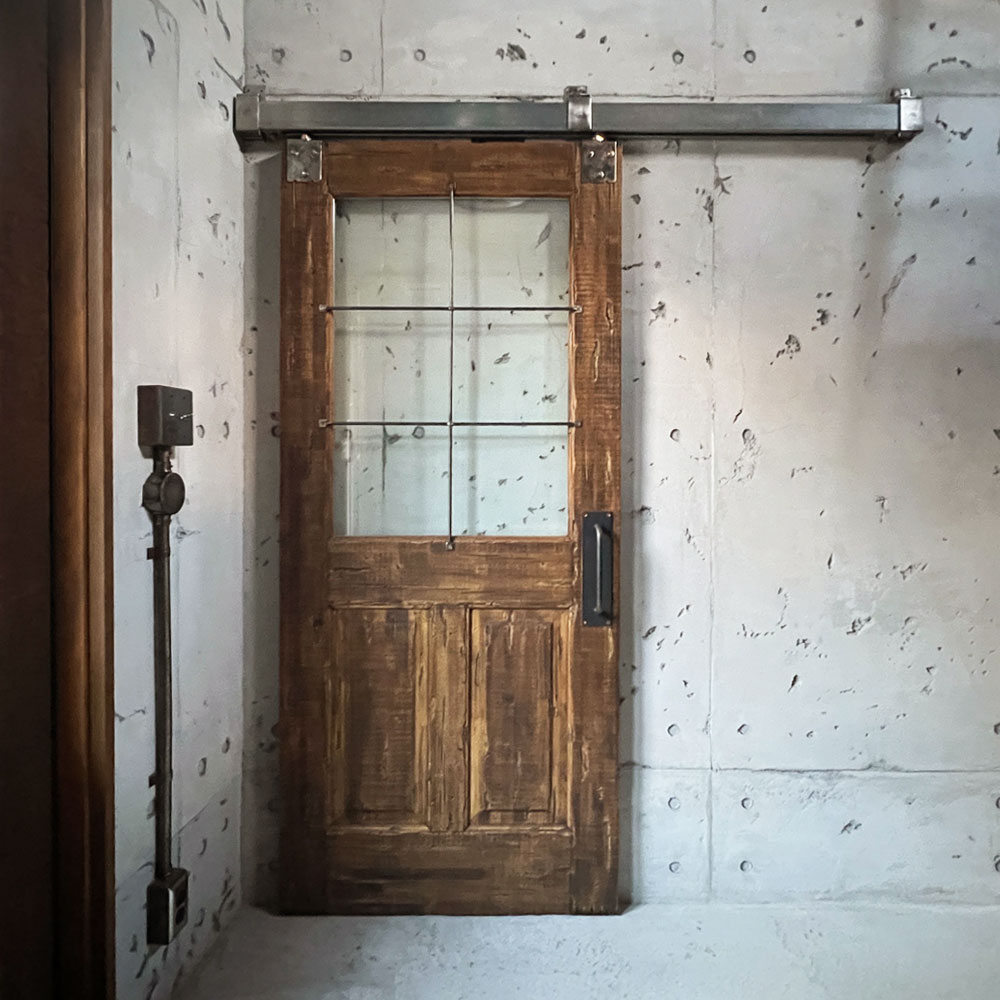 コンクリート壁に設置されたアメリカンヴィンテージ風バーンドア