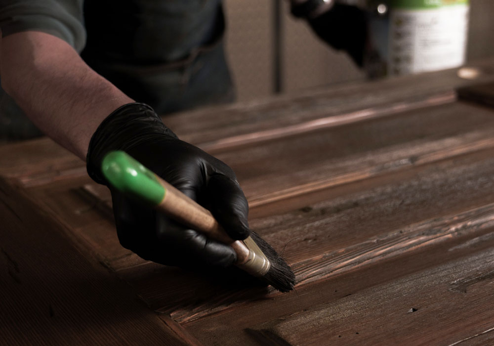 工房で木製ドアの塗装・仕上げを行う職人