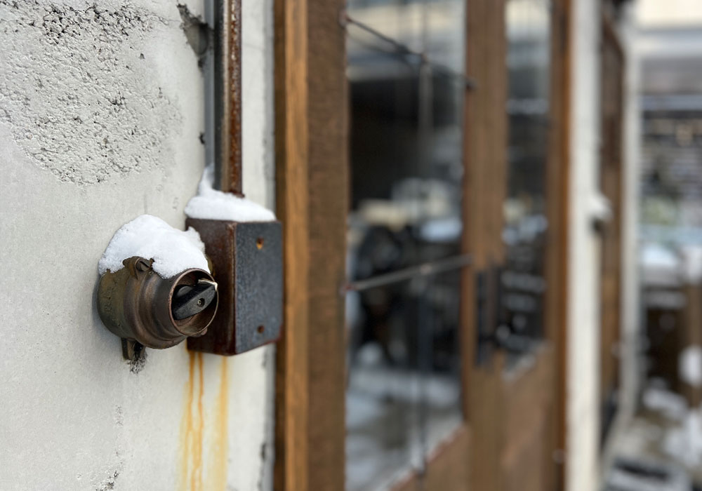錆びた鉄と雪が重なるドアのディテール