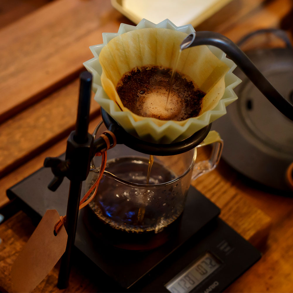 1. オーク材×鉄の重量感が、ドリップを安定させる：雪景色のショールームに佇む重厚なスタンド