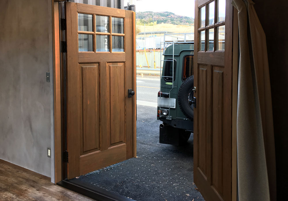 1. 「鉄×木」のコントラスト：モルタルの壁とヴィンテージ木製ドアの調和