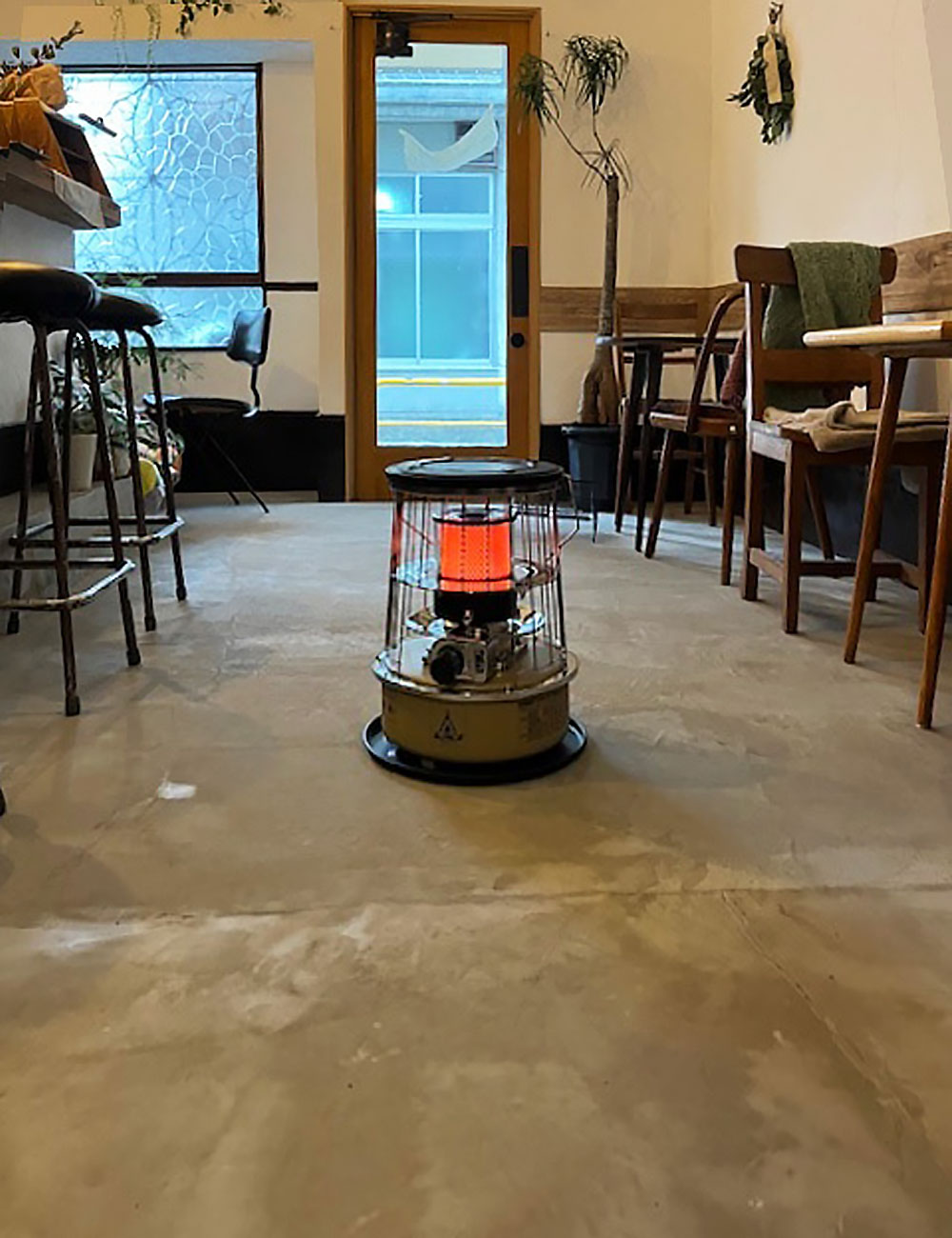 土間と木製ドアの調和：昭和レトロな空間に石油ストーブと光が差し込む風景