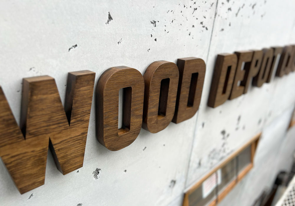 ショールームの壁面：コンクリートと木製の切り文字ロゴの対比