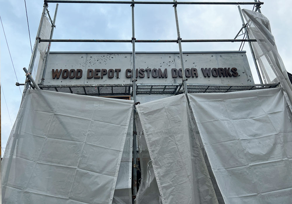 ショールーム製作工程：足場の隙間から見えるWOOD DEPOTの木製ロゴ