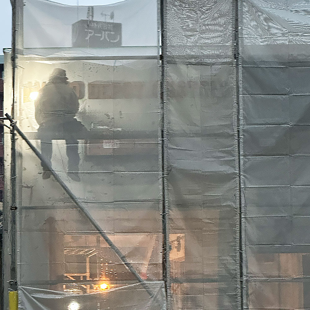 夕暮れのショールーム：投光器に浮かび上がる職人の手仕事のシルエット