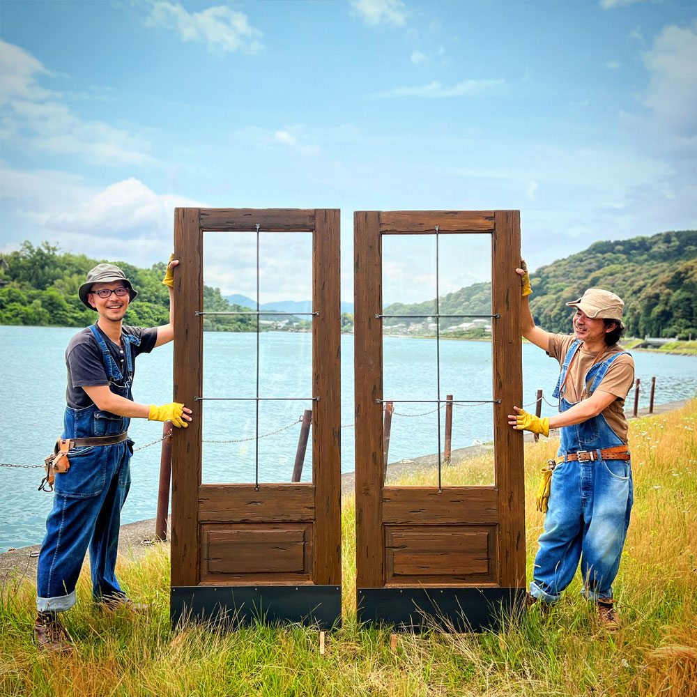 出荷を待つ仕上がりの良い木製ドアとスタッフ