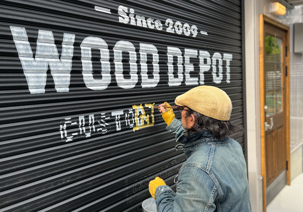 シャッターにロゴを手書きする北村の作業風景