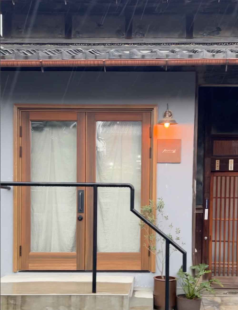 雨風の染み込みを愛おしむ「育てる外観」 しっとりと雨に濡れる両開き(観音開き)の木製ドア