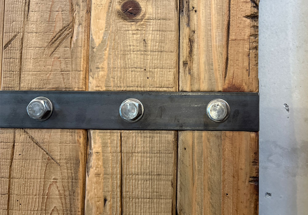 鉄のボルトがデザインのアクセントとなっている木製ドアのクローズアップ画像